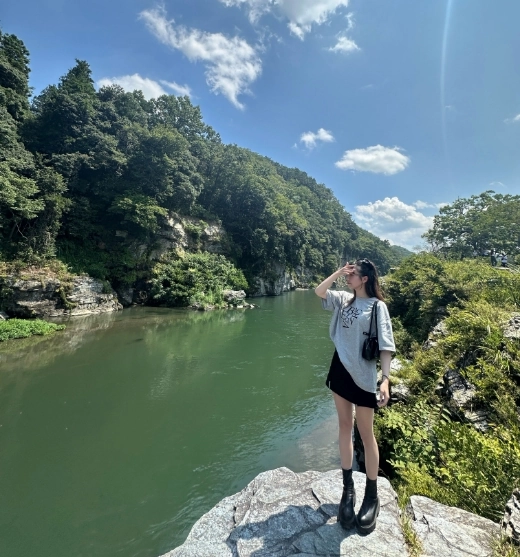 岩畳の上から渓谷を眺める人と夏空